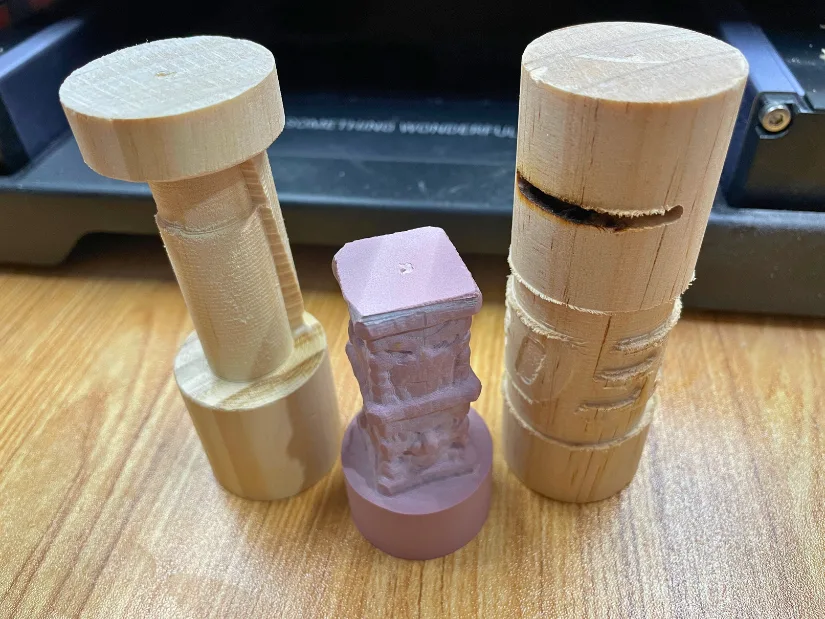 Three test pieces from Snapmaker 4-axis 性变视频 module showing failed attempts at carving, including rough shapes and incomplete 性发视频 logo engraving