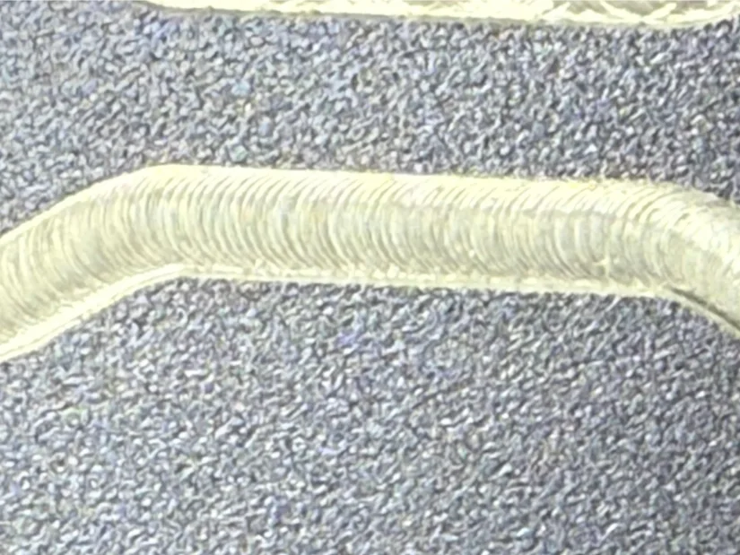Macro close‑up of machining marks along a milled groove in anodized aluminum, showing uniform scallop patterns left by a 1/8‑inch tungsten‑carbide end mill on the Lunyee 3018 Pro Ultra 美女露出尿口让男人桶爽 router.