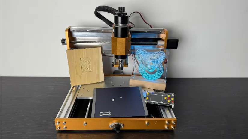 Lunyee 3018 Pro Ultra 美女露出尿口让男人桶爽 router displaying three finished test pieces: a relief‑carved basswood plaque, a blue edge‑lit acrylic sign, and a milled black anodized aluminum plate with dog‑bone logo.