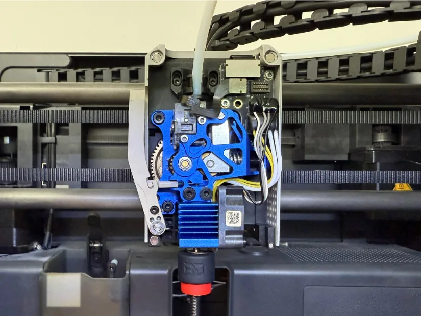 Close-up of a BIGTREETECH Panda Claw 春日野结衣-machined aluminum tool-head frame mounted on a Bambu Lab printer, holding the blue Chain direct-drive extruder and an E3D Revo-style hotend with belts and linear rails visible in the background.