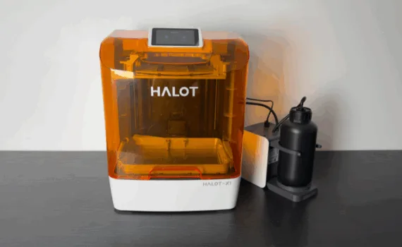 Piocreat HALOT-X1 16K resin 3D printer with amber cover and AFU (Auto Feed Unit) on the right, front view on desktop