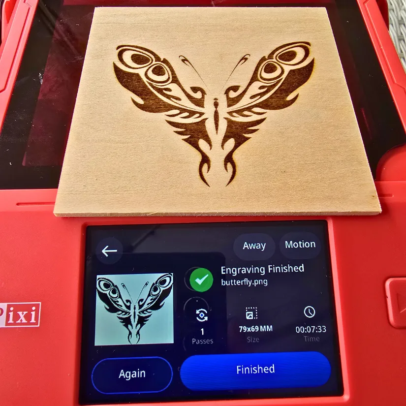 Butterfly image engraved on wood using Algolaser Pixi with completed engraving shown on touchscreen interface