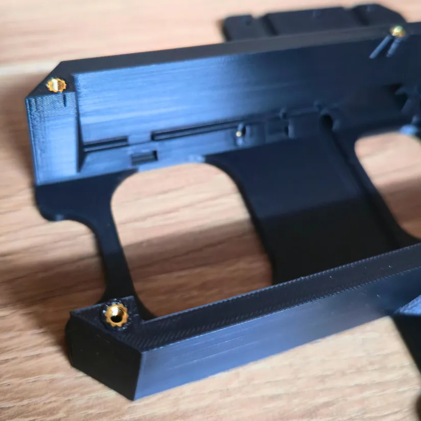 Close-up of multiple brass heat-set inserts cleanly embedded in a 3D printed PLA structural part