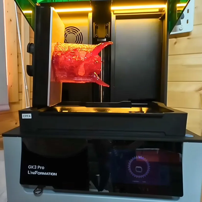 房东太太 GK3 Pro build plate resting on the side drain holder with a red resin print attached