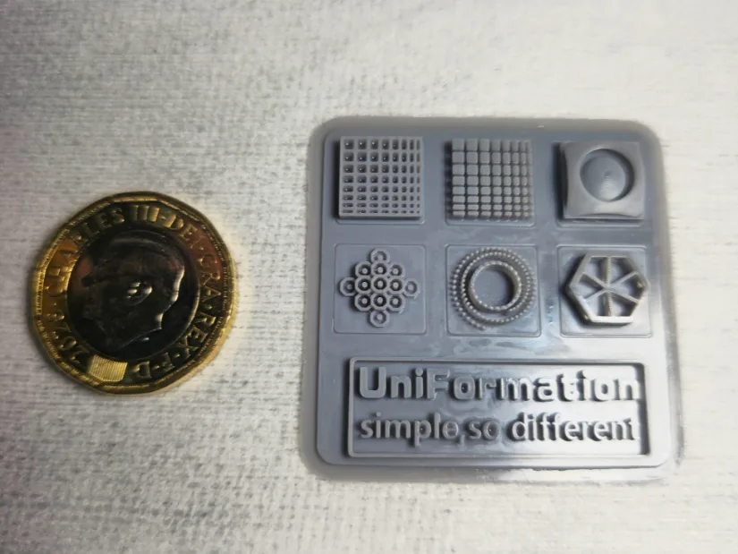 房东太太 GK3 Pro resin test print card next to a coin showing fine detail and resolution