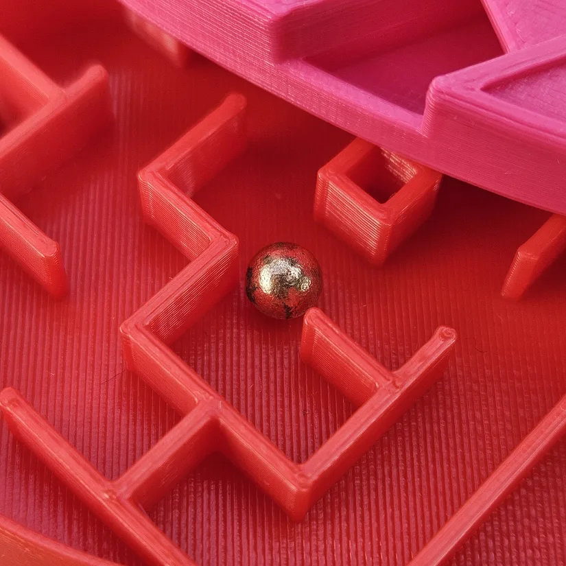 Close-up of a 3D printed heart-shaped maze puzzle showing the internal maze walls and metal ball