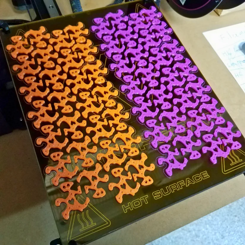 Heart-shaped tessellation pieces batch printed on a 3D printer build plate for classroom Valentine exchanges
